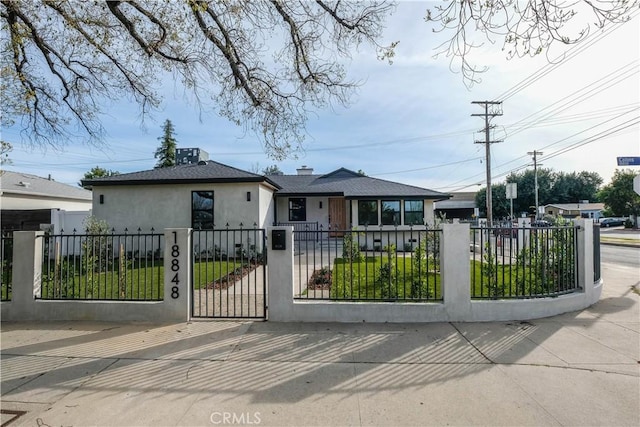 view of front of house featuring a fenced front yard, a gate, and stucco siding