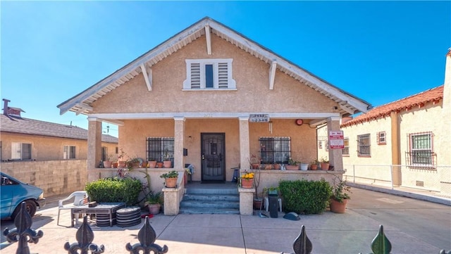 view of front of home featuring covered porch, fence, and stucco siding