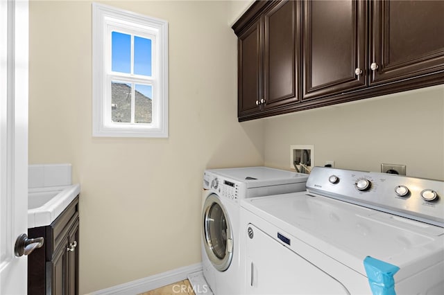 clothes washing area with baseboards, cabinet space, and separate washer and dryer