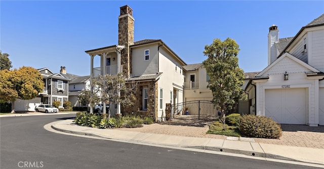 view of front facade featuring a residential view, decorative driveway, stone siding, an attached garage, and a gate