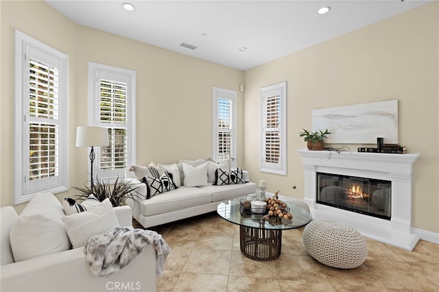 tiled living area with a glass covered fireplace, recessed lighting, visible vents, and a wealth of natural light