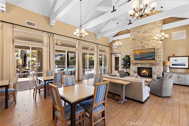 dining room with light wood-type flooring, visible vents, a notable chandelier, and high vaulted ceiling