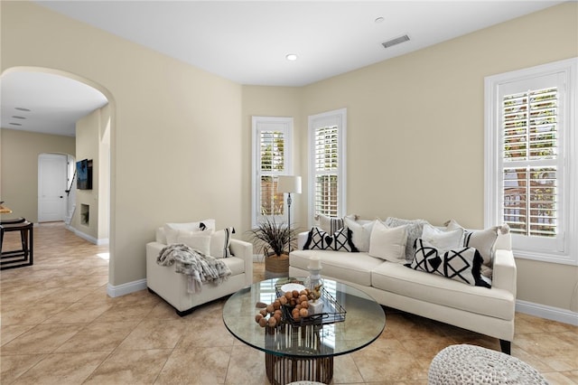 living area with visible vents, light tile patterned flooring, baseboards, and arched walkways