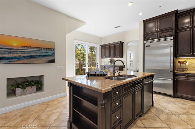 kitchen with light stone counters, light tile patterned flooring, appliances with stainless steel finishes, and a sink