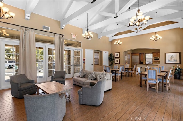 living area featuring wood finished floors, visible vents, plenty of natural light, arched walkways, and a chandelier