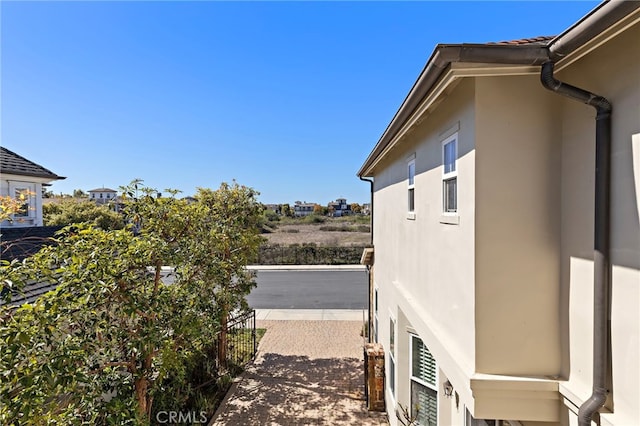 view of side of home with stucco siding and fence