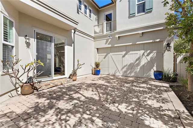 view of patio featuring a garage, decorative driveway, and a balcony