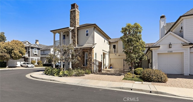 view of front of house with stone siding, decorative driveway, a garage, and a residential view