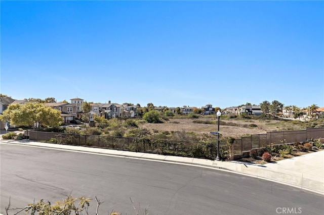 view of street with sidewalks, a residential view, curbs, and street lighting