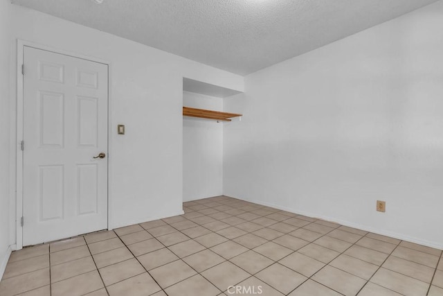 unfurnished room with a textured ceiling and light tile patterned floors