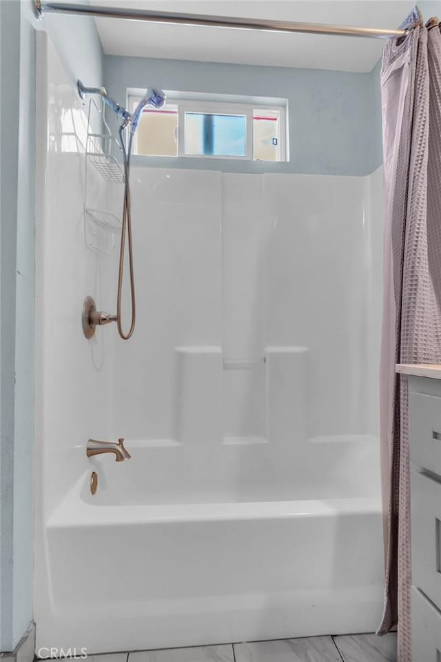 full bath featuring marble finish floor and shower / bath combo