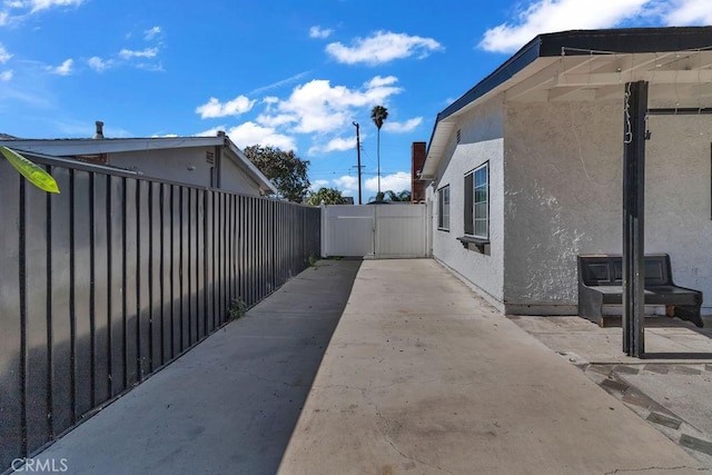 view of side of property with a gate, fence, a patio, and stucco siding