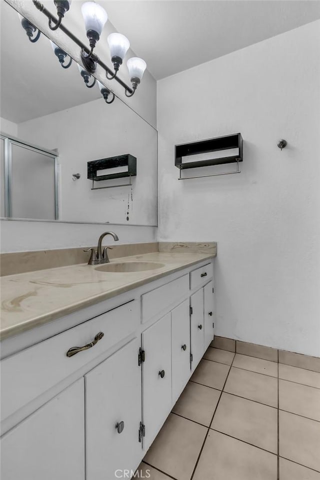 bathroom with a stall shower, tile patterned flooring, vanity, and an inviting chandelier