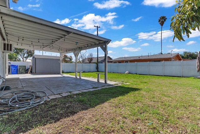 view of yard with an outbuilding, a fenced backyard, a carport, a shed, and a patio area