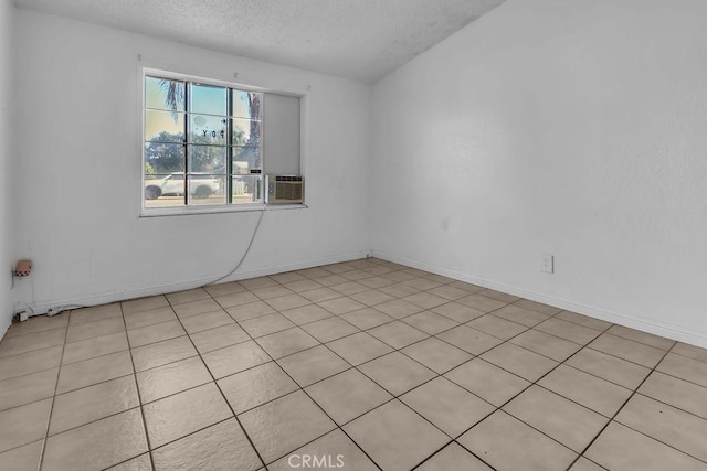 spare room featuring cooling unit, baseboards, and a textured ceiling