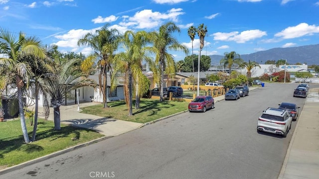 view of road with curbs, a residential view, and a mountain view