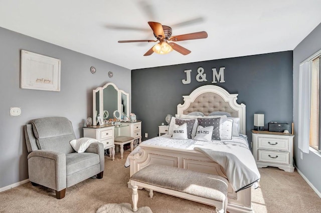 bedroom featuring an accent wall, light carpet, baseboards, and a ceiling fan