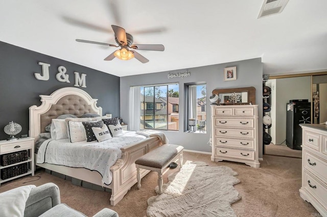 bedroom featuring baseboards, visible vents, a ceiling fan, and light colored carpet