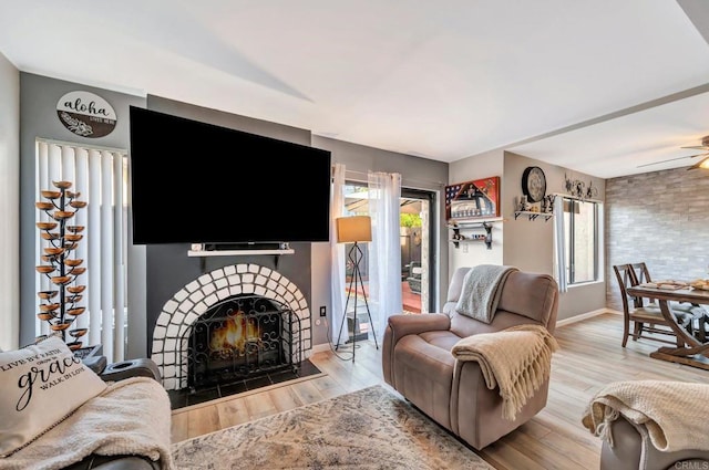 living area with ceiling fan, baseboards, wood finished floors, and a tile fireplace