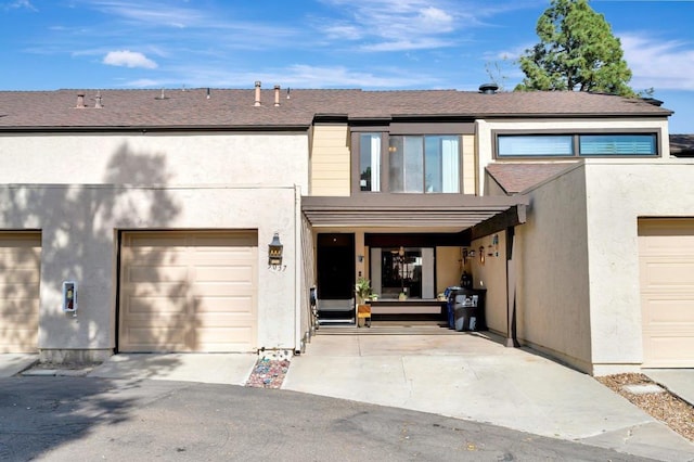 exterior space featuring a garage, driveway, a shingled roof, and stucco siding