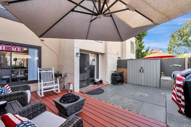 wooden deck with an outdoor fire pit, a patio area, and fence