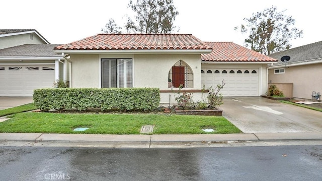 mediterranean / spanish house with stucco siding, concrete driveway, an attached garage, and a tiled roof