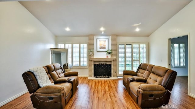 living room with a brick fireplace, baseboards, lofted ceiling, and wood finished floors