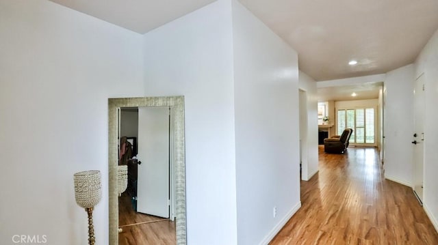 corridor featuring light wood-type flooring and baseboards