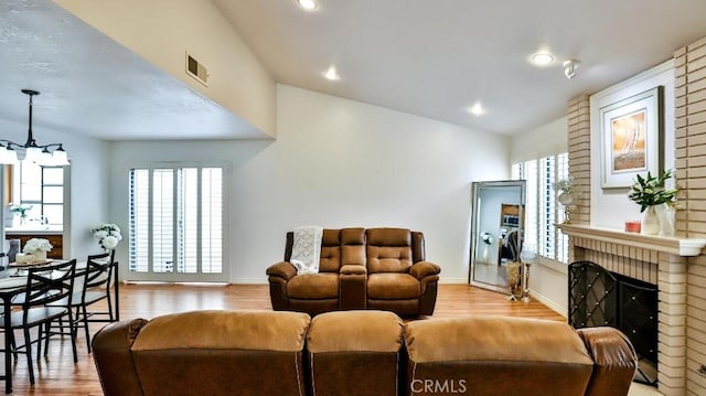 living room with wood finished floors, plenty of natural light, a fireplace, and visible vents