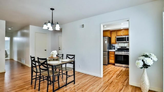 dining area with an inviting chandelier, light wood-style floors, visible vents, and baseboards