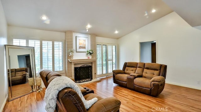 living room featuring a brick fireplace, baseboards, lofted ceiling, recessed lighting, and light wood-style floors