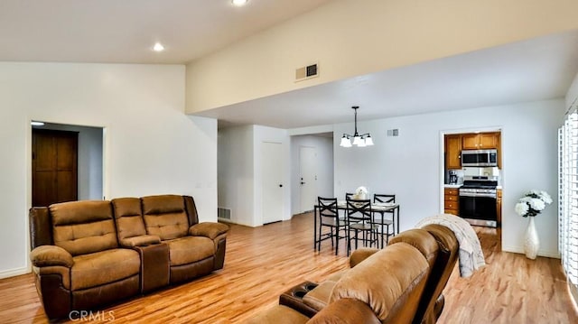 living room with visible vents, light wood finished floors, a notable chandelier, and vaulted ceiling