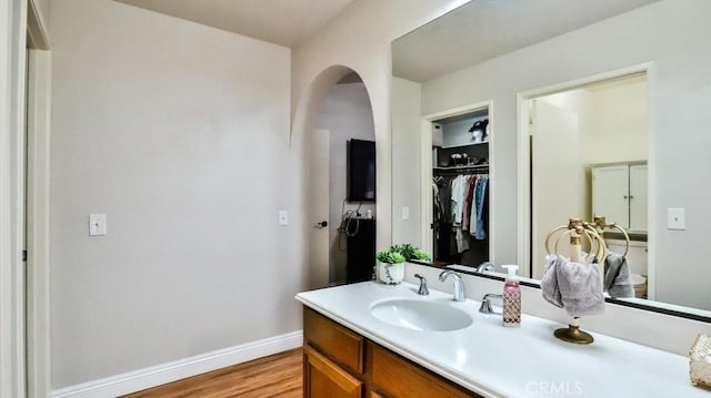 bathroom with baseboards, wood finished floors, and vanity