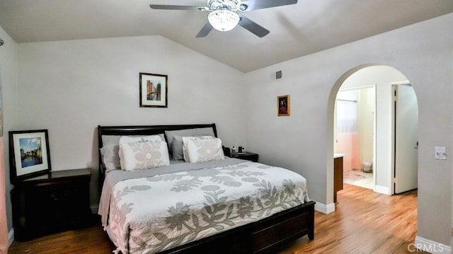 bedroom with visible vents, arched walkways, lofted ceiling, and wood finished floors