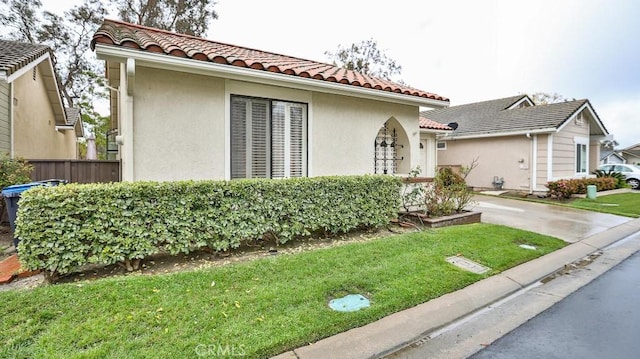 view of front facade with stucco siding, a front lawn, and a tiled roof