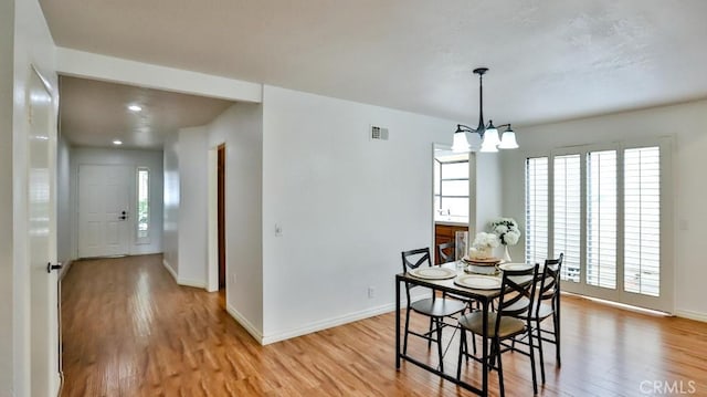 dining room with a chandelier, visible vents, light wood finished floors, and baseboards