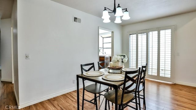 dining room featuring a chandelier, baseboards, a healthy amount of sunlight, and wood finished floors