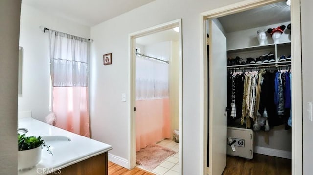 bathroom featuring a spacious closet, vanity, a shower with shower curtain, and baseboards