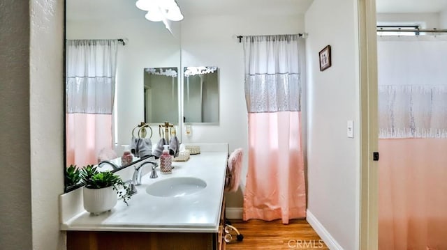 full bathroom featuring vanity, baseboards, and wood finished floors