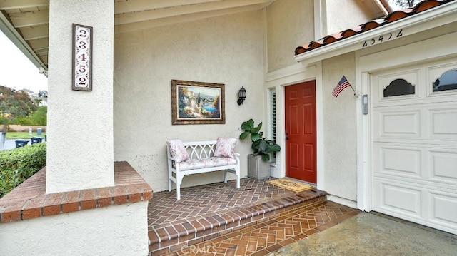 property entrance with covered porch and stucco siding