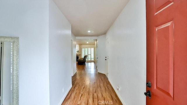 hall with baseboards and light wood-style floors