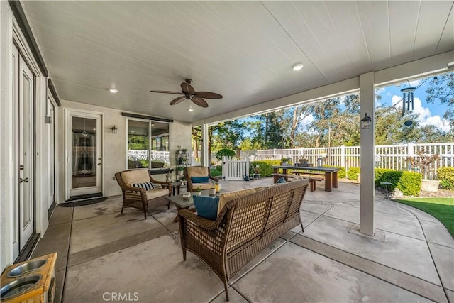 view of patio with outdoor dining space, ceiling fan, an outdoor living space, and fence