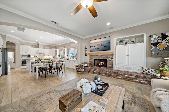 living room featuring arched walkways, a healthy amount of sunlight, visible vents, and a fireplace