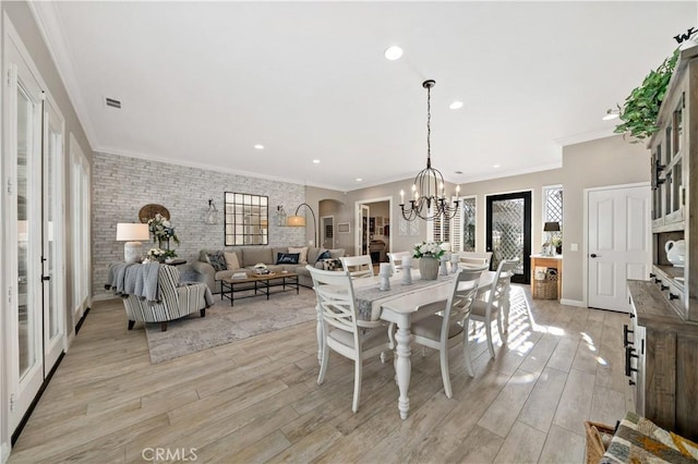 dining area with arched walkways, visible vents, light wood finished floors, and an inviting chandelier