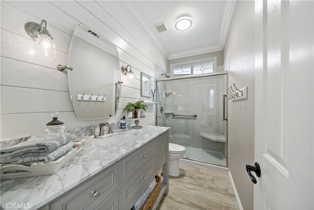 bathroom with toilet, ornamental molding, a shower stall, vanity, and wood finished floors