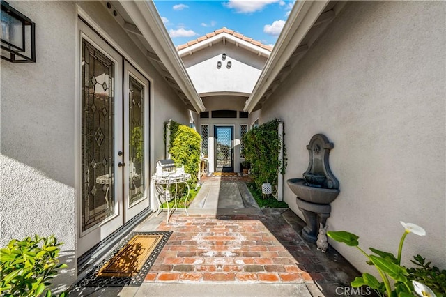 entrance to property featuring a patio area, a tiled roof, and stucco siding