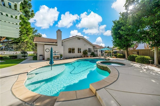 view of swimming pool with a pool with connected hot tub, a patio area, and fence