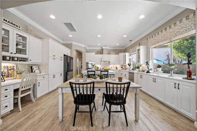 kitchen featuring white cabinets, light wood-style floors, arched walkways, and stainless steel appliances