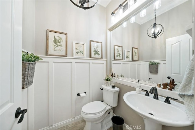 bathroom featuring a sink, a decorative wall, and toilet