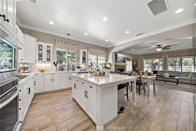 kitchen with a fireplace, visible vents, appliances with stainless steel finishes, wood tiled floor, and open floor plan